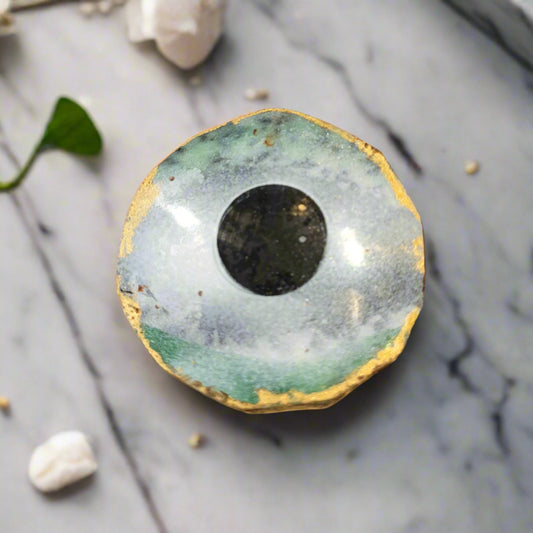 geometric shaped chocolate cookie pained with white and green to resemble a frozen lake with coconut and hazelnut inside