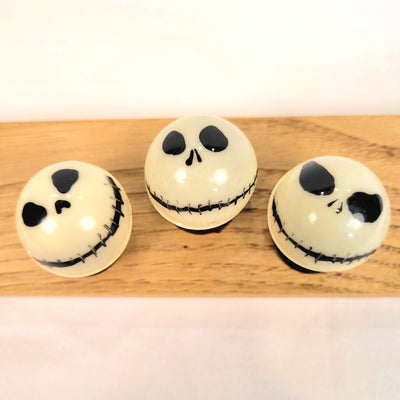 Three white spherical ornaments with black facial features of Jack Skellington
