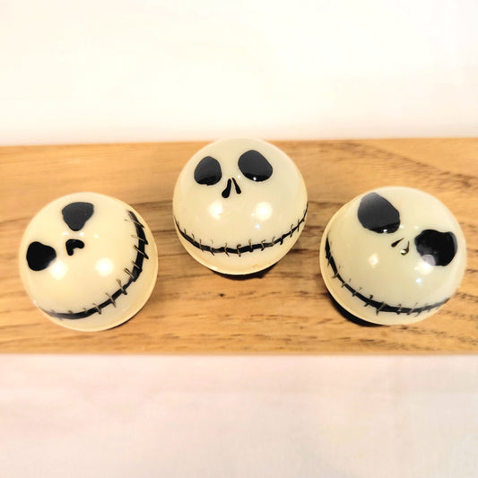 Three white spherical ornaments with black facial features of Jack Skellington