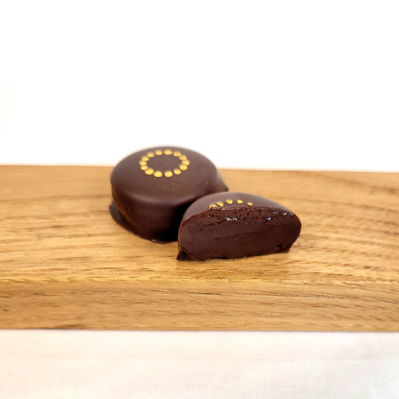 Two chocolate truffles on a wooden board with a white background