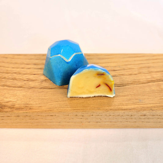 blue geometric-shaped bonbon flavored with saffron and honey cut open to see inside