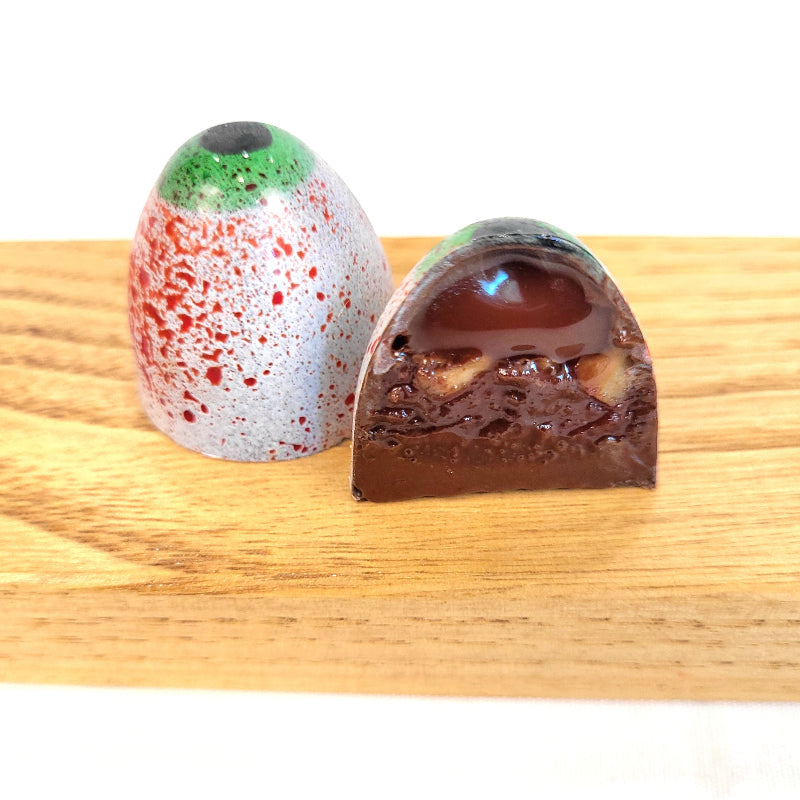 chocolate bonbon painted to look like a spooky eyeball cut open to see caramel and ganache inside