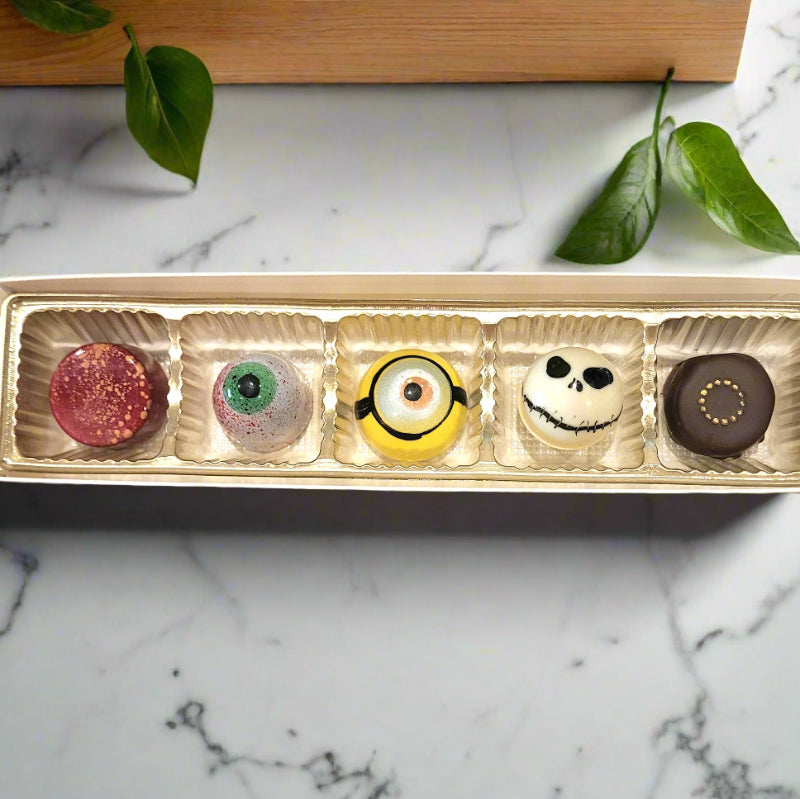 Assorted Halloween-themed bonbons in a decorative box on a marble surface.