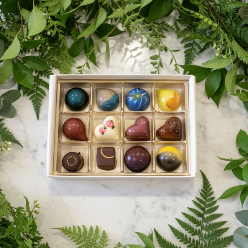 box of chocolates on a counter surrounded by greenery