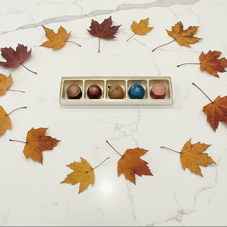 Five colorful chocolates in a row on a granite countertop