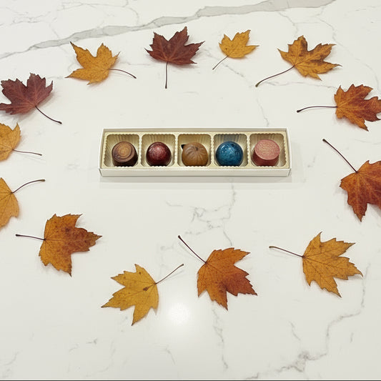 Five colorful chocolates in a row on a granite countertop